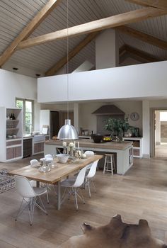 a large open concept kitchen and dining room with wood flooring, white walls and ceiling