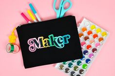 a black zipper bag with the word maker on it next to craft supplies and scissors