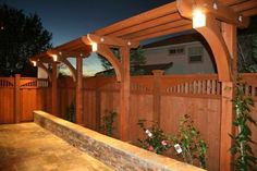 a wooden fence with lights on it and flowers growing in the corner next to it