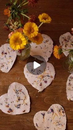 some flowers are sitting in vases on a table with paper hearts and other items