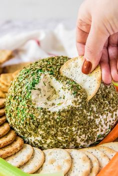 a person dipping something into a cracker on top of a platter of crackers