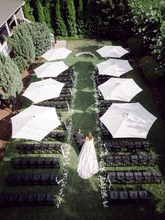 a bride and groom sitting under umbrellas in the grass at their outdoor wedding ceremony