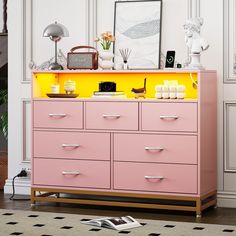 a pink and yellow dresser in a white room with pictures on the wall behind it