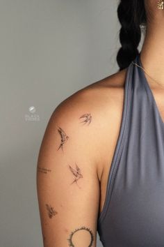 a woman with tattoos on her arm and shoulder is looking at the camera while wearing a gray top