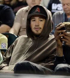 a man in a hoodie looking at his cell phone while sitting next to other people