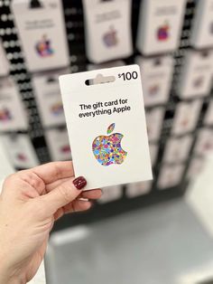 a person holding up an apple gift card in front of a rack of other cards