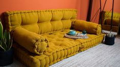 a yellow couch sitting on top of a carpeted floor next to a potted plant