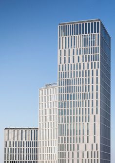 two tall buildings sitting next to each other on top of a grass covered field in front of a blue sky