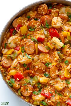 a pan filled with rice and shrimp on top of a white table next to a fork