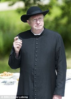 a man in a black outfit and hat standing next to a table with food on it