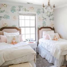 two twin beds in a bedroom with floral wallpaper and chandelier hanging from the ceiling