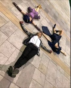 three women laying on the ground in front of a building with their legs spread out