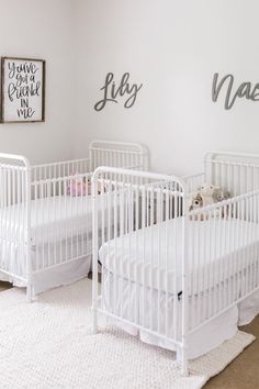 three white cribs in the corner of a room with two baby's names on the wall