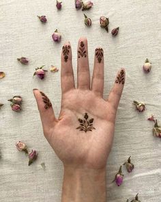 a person's hand with tattoos on it and rose petals scattered around the fingers