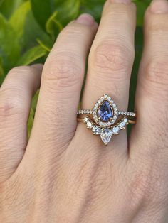 a woman's hand holding a ring with an oval shaped tan and white diamond