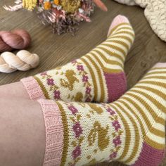 the legs of a person wearing socks with flowers and seashells in the background