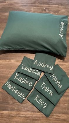 four pillow cases with names on them sitting on a wooden floor