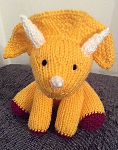 a knitted yellow dog sitting on top of a gray table next to a white wall