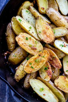 cooked potatoes with parsley in a skillet on a wooden table, ready to be eaten