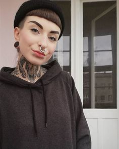 a woman with tattoos and piercings on her face