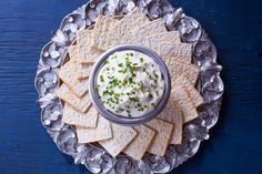 crackers with sour cream and chives in a bowl on a silver platter