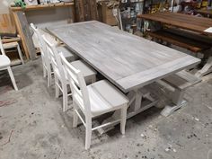 a table with six chairs around it in a room filled with other furniture and tools