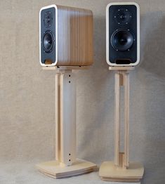 two speakers on wooden stands with one standing up and the other sitting back to back