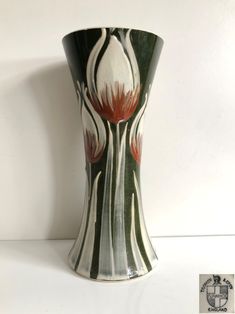 a white and green vase with red flowers on it