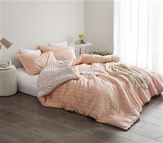 an unmade bed with pink comforter and pillows on it in a white room