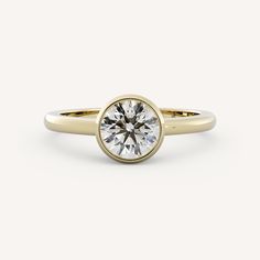 a yellow gold ring with a round diamond in the center, on a white background