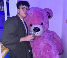 a man standing next to a giant pink teddy bear