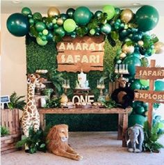 an animal themed birthday party with green balloons and greenery on the wall behind it