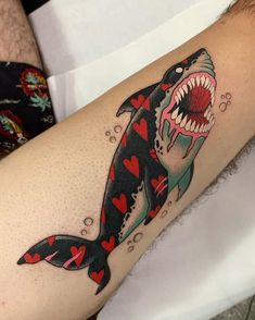 a man with a shark tattoo on his arm holding a red heart in the other hand