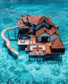 an aerial view of a house on stilts in the middle of clear blue water