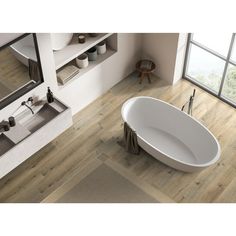 a bathtub sitting on top of a wooden floor next to a sink and mirror