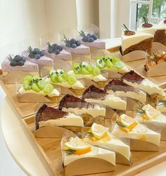 a wooden tray topped with lots of different types of cheeses and fruit on top of it