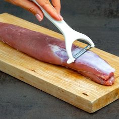 a person is cutting meat on a wooden board