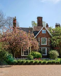 a large brick house surrounded by trees and flowers