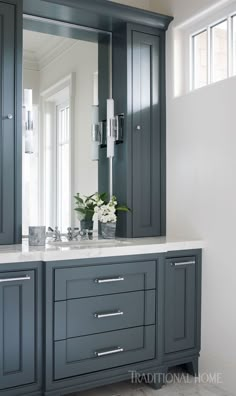 a bathroom with gray cabinets and a large mirror