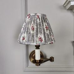 a lamp is on the wall next to a light fixture with a flowered shade