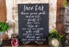 a chalkboard sign sitting on top of a wooden table next to potted plants