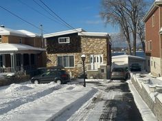 two cars parked on the side of a snow covered road in front of some houses