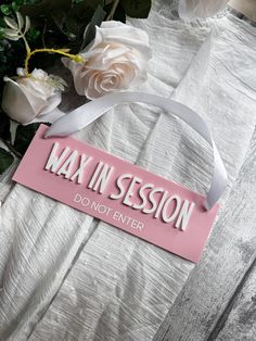 a pink sign that says wax in session don't enter next to some flowers