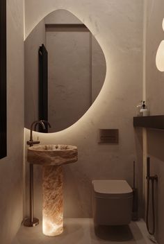 a bathroom with a toilet, sink and mirror in it's corner area at night