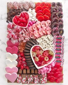 an assortment of heart shaped candies and chocolates arranged on a board with paper hearts