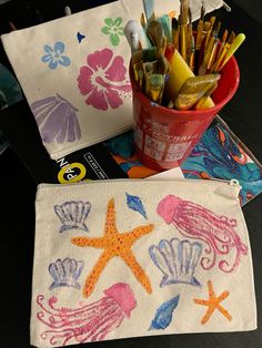 two pencils are sitting on top of a table next to a cup with pens and markers in it