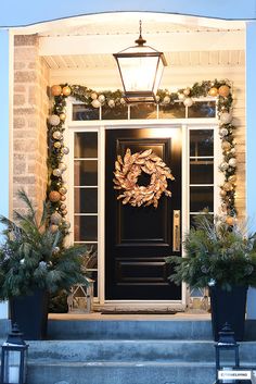 a front door with two planters and a wreath on it