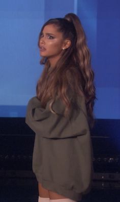 a woman with long hair standing in front of a tv screen and wearing white stockings