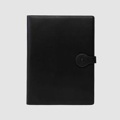 a black leather notebook with a button on the front and an empty page in the middle