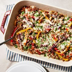 a casserole dish with meat and vegetables in it on a blue and white striped cloth